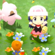 A young Pokémon trainr stands amid her Pokémon, arms in the air. They are surrounded by a field of flowers.